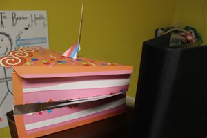 The piece of cake holds students' birthdays cards (which also contain a special birthday gift!).